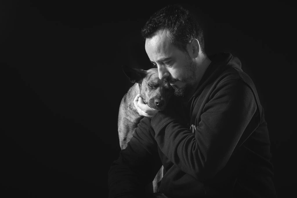 Retrato en blanco y negro de un hombre abrazando a su perro